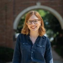 lady with auburn hair, glasses and dark denim button up shirt